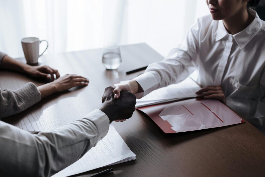Professional handshake between diverse individuals over a business contract indoors.